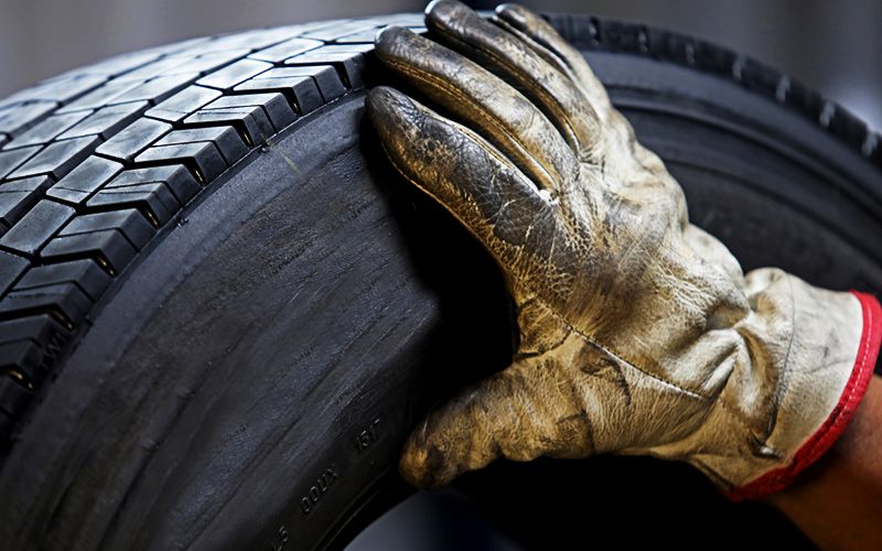 Runderneuerter-Reifen Hand gleitet über runderneuerten Pneu